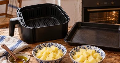 Zwei rohe Kartoffelportionen, Airfryerkorb und Backblech für einen Gerätevergleich