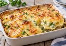 Cremiger Erbsen-Kartoffel-Auflauf mit goldbrauner Käsekruste und Sahnesoße, eine Portion wird aus der Form gehoben.