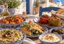 Griechische Gerichte auf einem rustikalen Tisch mit gefüllten Paprika, Bohnen und Dips