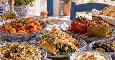 Griechische Gerichte auf einem rustikalen Tisch mit gefüllten Paprika, Bohnen und Dips