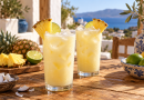 Zwei Gläser cremige Kokos-Inselbrise mit Eis, Ananas und Limette auf einem Holztisch