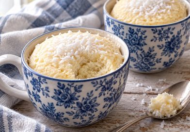 Kokos-Tassenkuchen mit Hüttenkäse für 2 Tassen Zwei Kokos-Tassenkuchen mit Hüttenkäse in blau-weißen Tassen, einer mit ausgelöffeltem Stück und Kokosraspeln.
