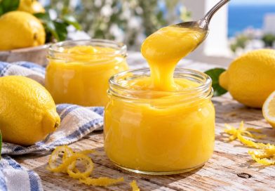 Lemon Curd mit ganzer Zitrone in zwei Gläsern mit Zitronen und einem Löffel Zitronencreme.