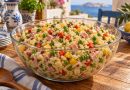 Bunter Kritharaki-Nudelsalat mit Paprika, Erbsen, Gouda und Kochschinken in einer Glasschüssel