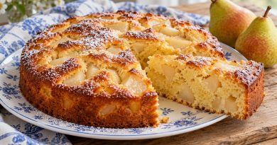 Saftiger Birnen-Vanille-Kuchen mit sichtbaren Birnenstücken und Puderzucker, angeschnitten auf einem blau-weißen Teller.