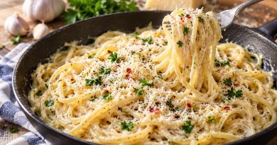 Parmesan-Spaghetti mit Knoblauchcreme, Petersilie und feinen Chiliflocken in einer Pfanne, auf einer Gabel aufgedreht.